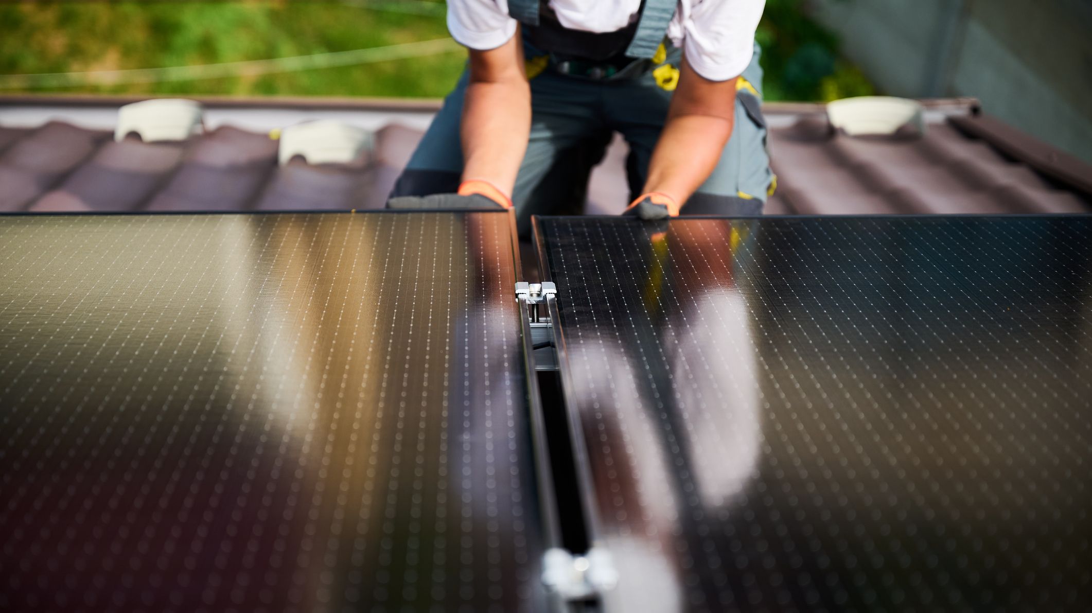 Un installeur pose des panneaux solaires photovoltaïques sur le toit d'une maison.