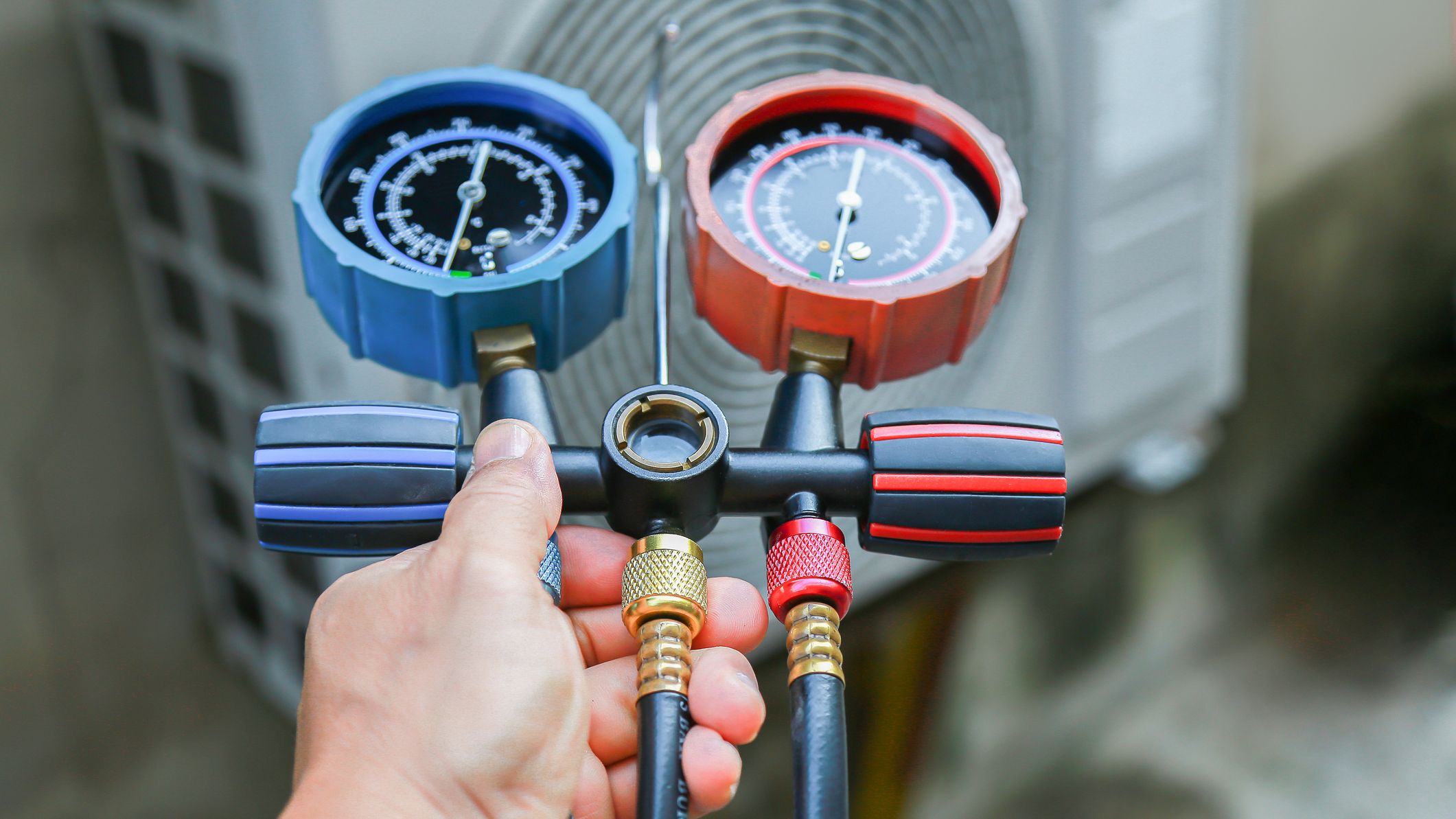 Photo d'illustration d'un technicien CVC vérifiant la quantité de fluides réfrigérants d'un système de climatisation.