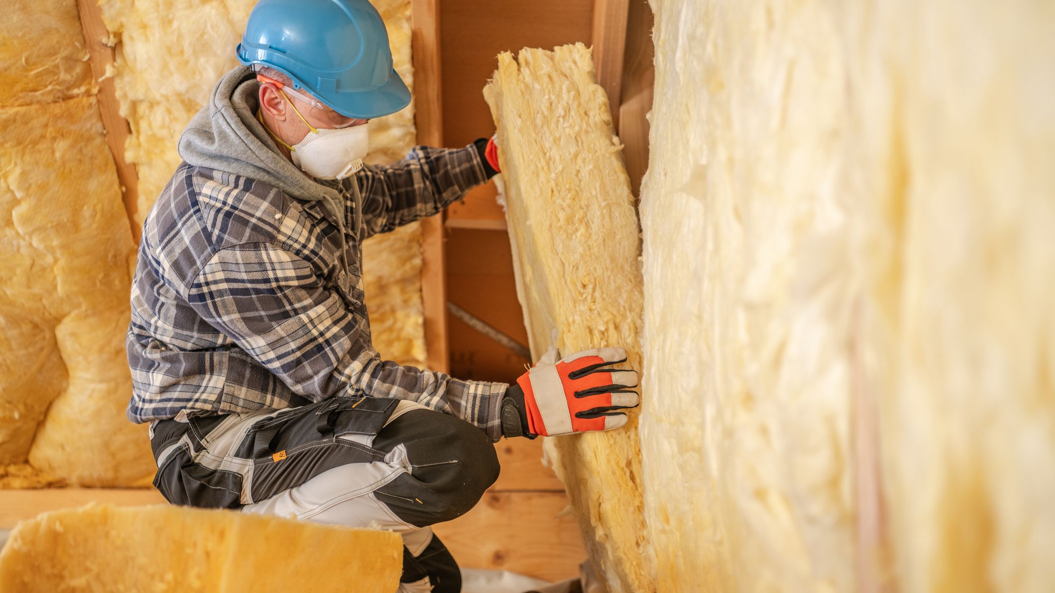 Un ouvrier du bâtiment réalisant l'isolation thermique d'un logement en cours de rénovation.