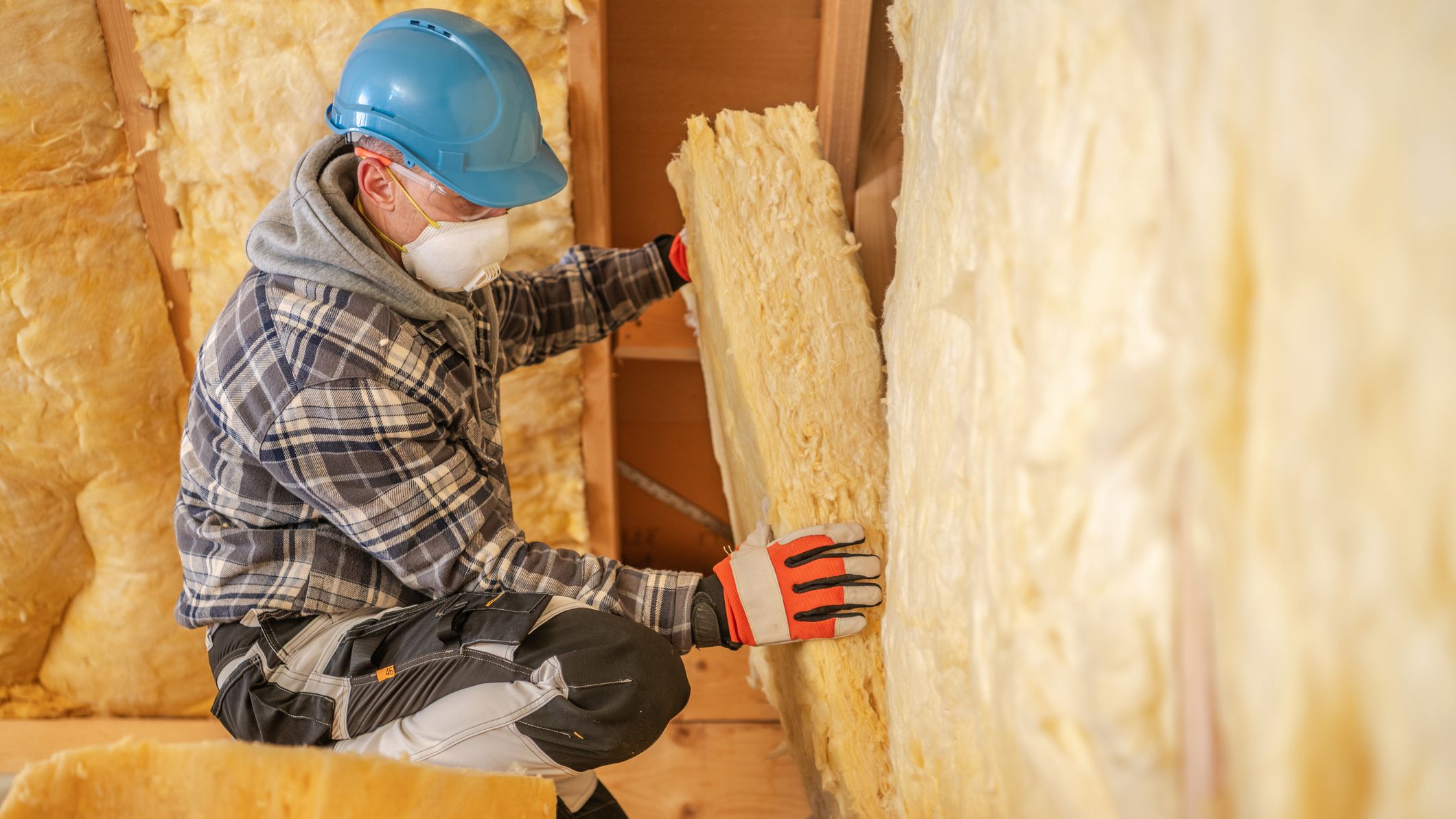 Un ouvrier du bâtiment réalisant l'isolation thermique d'un logement en cours de rénovation.