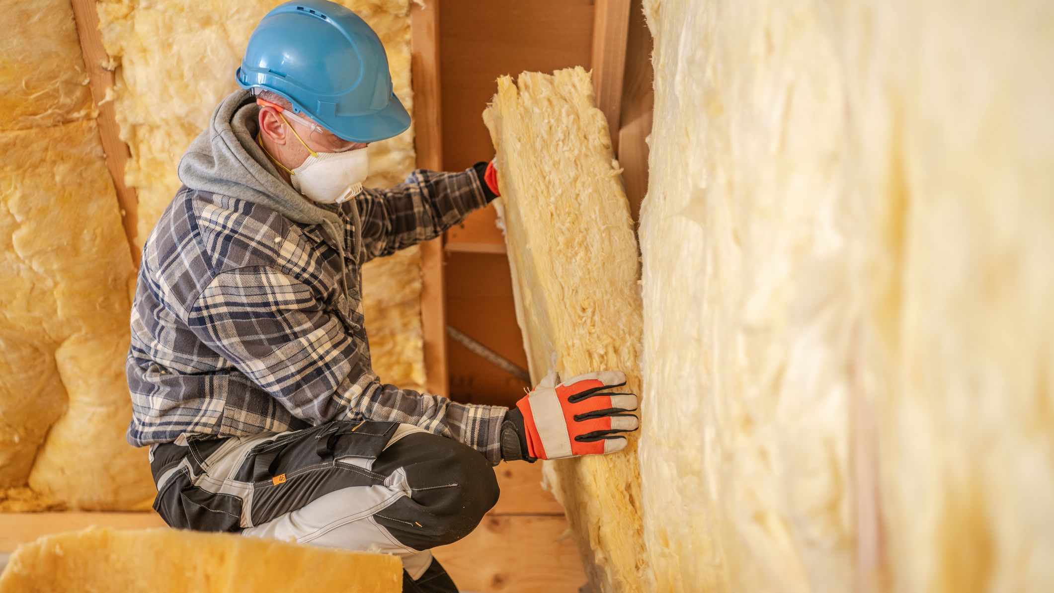 Un ouvrier du bâtiment réalisant l'isolation thermique d'un logement en cours de rénovation.