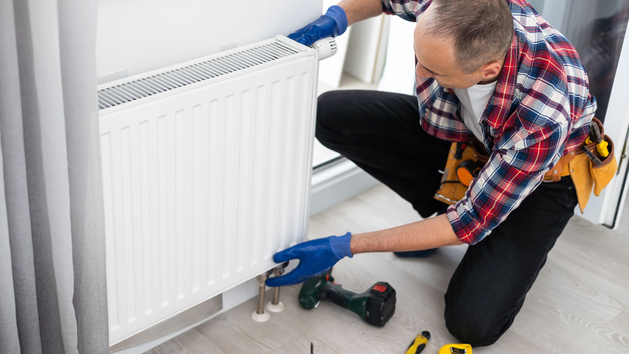 Un installateur équipe un logement d'un radiateur.