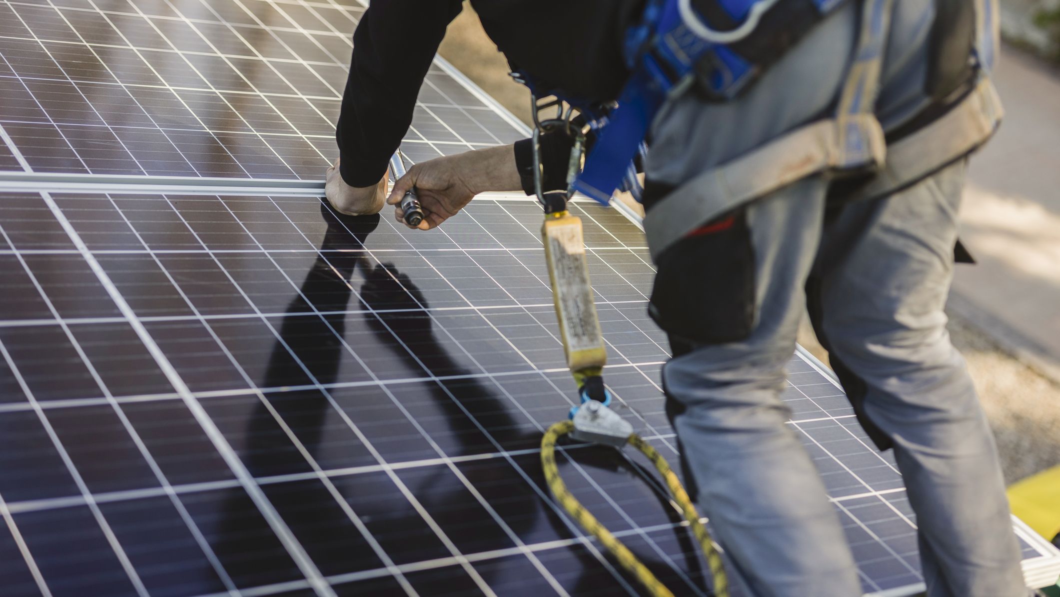 Un installateur pose un panneau solaire photovoltaïque sur le toit d'un bâtiment.
